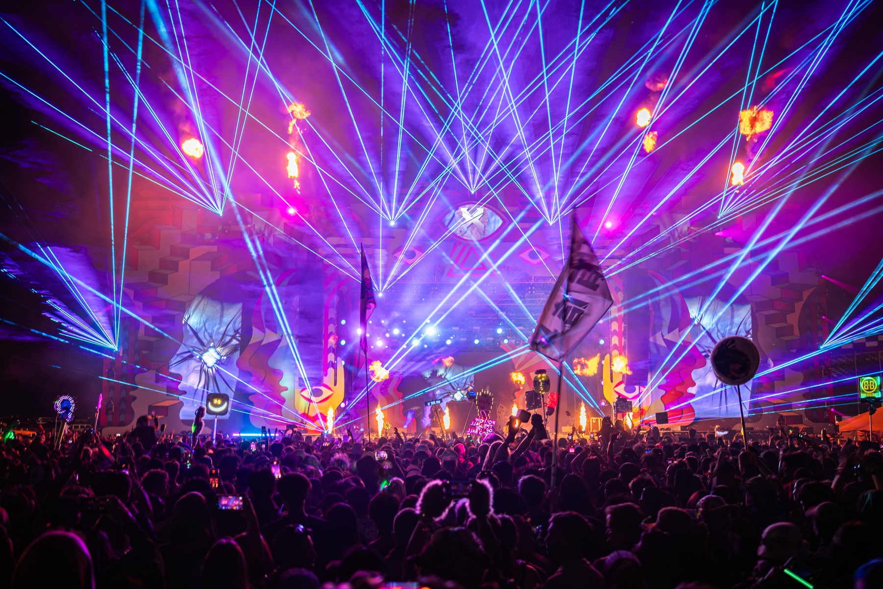 Festival crowd under purple lighting and laser beams at night
