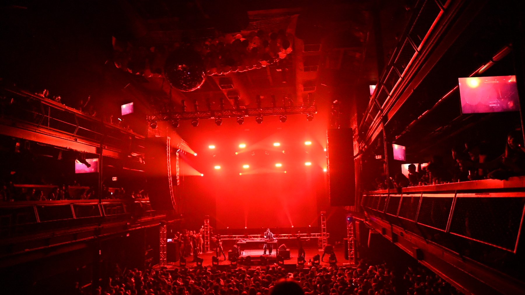 Indoor concert venue with truss, lighting rig and red wash over the stage